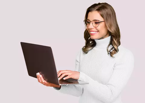 Lächelnde Frau mit Brille, die einen Laptop hält